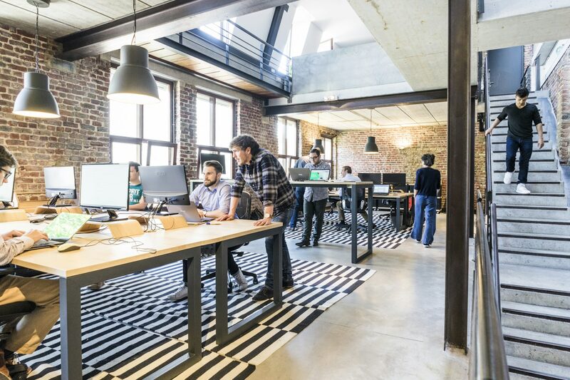 Open-plan workspace with team members collaborating at standing desks