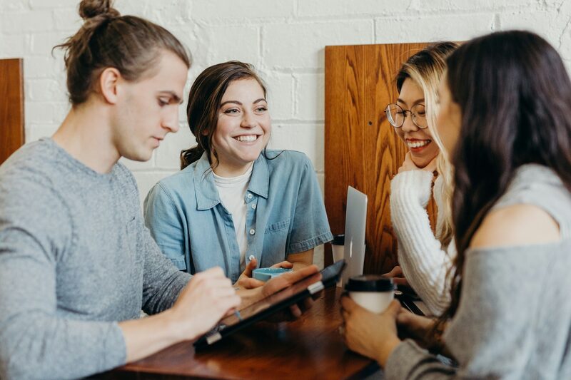 Four young marketing team members talking and smiling around a table